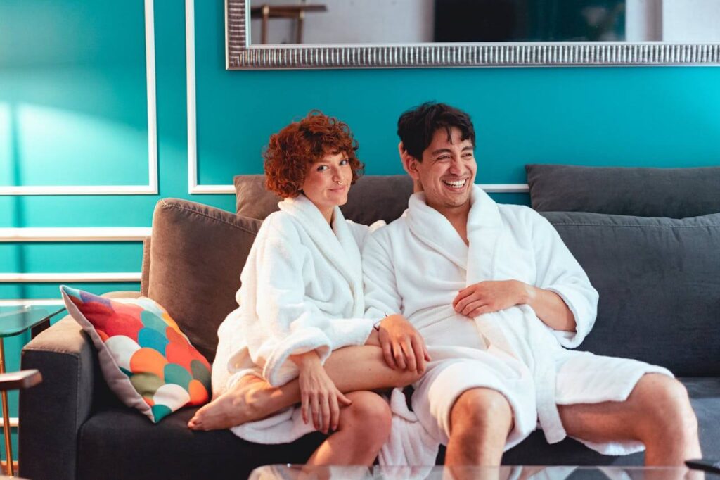 Mann und Frau in Bademantel lächeln verschmitzt